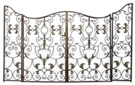 A pair of French wrought iron gates, c.1900, decorated with sinuous scrolls and applied with brass
