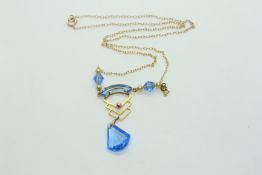 AN ART DECO YELLOW METAL PENDANT NECKLACE WITH A BLUE GLASS DROP (RUBBED MARKS) L 40CM.