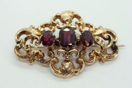AN ELABORATE VICTORIAN YELLOW METAL OPENWORK BROOCH SET WITH AMETHYST PANELS,