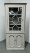 A WHITE PAINTED PINE HALF GLAZED CORNER CUPBOARD.