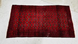A RED PATTERNED EASTERN RUG 190CM X 105CM.