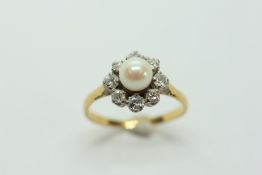 AN 18CT GOLD PLATINUM SET PEARL AND DIAMOND RING, THE CENTRAL PEARL SURROUNDED BY EIGHT DIAMONDS.