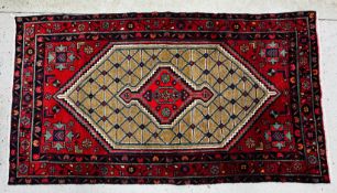 A RED PATTERNED EASTERN CARPET 233 X 128CM.