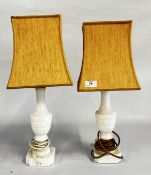 A PAIR OF POLISHED HARDSTONE TABLE LAMPS WITH MUSTARD SHADES - SOLD AS SEEN.