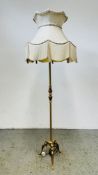 AN ORNATE BRASSED LAMP STANDARD WITH CREAM FRINGED SHADE - SOLD AS SEEN.