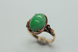 A JADE RING, THE OVAL STONE CLAW SET ON A 14CT GOLD BAND.