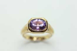 A 9CT GOLD RING SET WITH OVAL AMETHYST.