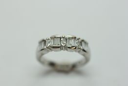 A DIAMOND RING, FOUR PANELS EACH WITH BAGUETTE TYPE DIAMONDS, DIVIDED BY THREE NAVETTE CUT DIAMONDS,