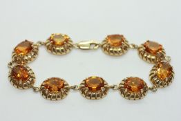A 9CT GOLD BRACELET SET WITH NINE OVAL CITRINES.