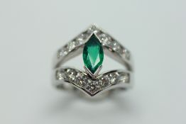AN EMERALD AND DIAMOND SET RING, THE CENTRAL NAVETTE CUT STONE BETWEEN TWO SHAPED BANDS,