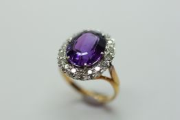 AN AMETHYST AND DIAMOND RING, THE OVAL CUT CENTRAL STONE SURROUNDED BY BRILLIANT CUT DIAMONDS,