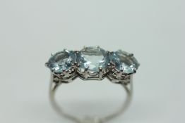 AN AQUAMARINE TRIO RING, THE THREE CIRCULAR STONES CLAW SET ON A PLATINUM BAND.