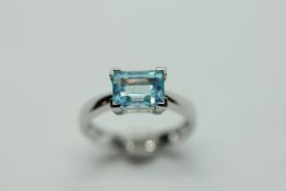 AN AQUAMARINE RING, THE SINGLE BAGUETTE STONE CLAW SET ON A 9CT WHITE GOLD BAND.