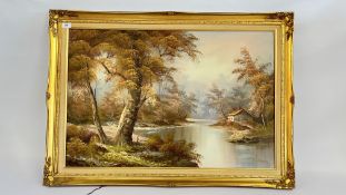 A GILT FRAMED AND MOUNTED OIL ON CANVAS DEPICTING A RURAL COTTAGE ON A RIVER BANK SCENE BEARING