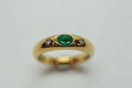 AN EMERALD AND DIAMOND RING, THE CENTRAL OVAL STONE IN A RUB OVER SETTING,