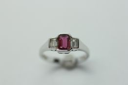 A RUBY AND DIAMOND RING, THE CENTRAL STONE FLANKED BY TWO SMALLER BAGUETTE CUT DIAMONDS,