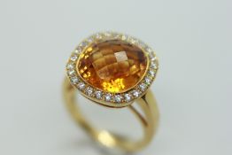 A CITRINE RING, THE CENTRAL FACETED STONE SURROUNDED BY SMALL DIAMONDS MARKED 750.