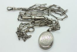 AN UNUSUAL WHITE METAL WATCH CHAIN WITH AN OVAL PHOTO LOCKET ENGRAVED WITH A HERALDRIC CREST.