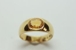 AN 18CT YELLOW GOLD BAND RING SET WITH OVAL CITRINE IN RUB OVER SETTING.