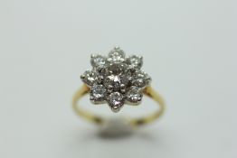 A DIAMOND FLOWER HEAD RING, THE CENTRAL BRILLIANT CUT STONE APPROXIMATELY 5MM IN DIAMETER,