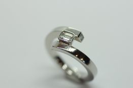 A MODERN CONTEMPORARY PLATINUM CROSSOVER RING SET WITH A SINGLE BAGUETTE DIAMOND WITH TWO SMALL
