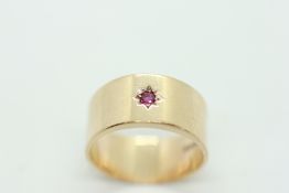 9CT GOLD BAND RING SET WITH SINGLE SMALL RUBY IN STAR BURST SETTING.