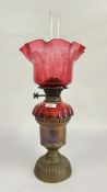 ANTIQUE BRASS BASED OIL LAMP WITH CRANBERRY GLASS SHADE AND FONT.