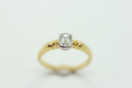AN 18CT YELLOW GOLD RING, THE SINGLE BAGUETTE CUT DIAMOND IN A WHITE GOLD SETTING.