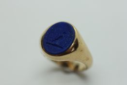 A 9CT GOLD AND LAPIS LAZULI SIGNET RING ENGRAVED WITH THE CREST OF A BIRD.