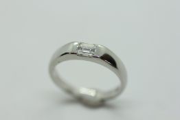 A PLATINUM SOLITAIRE RING, THE BAGUETTE STONE IN A RUB OVER SETTING.