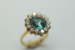 AN AQUAMARINE AND DIAMOND RING, THE PRINCIPAL CIRCULAR STONE SURROUNDED BY FOURTEEN SMALL,