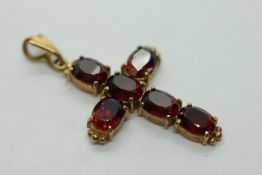 A 9CT YELLOW GOLD GARNET SET CROSS PENDANT.