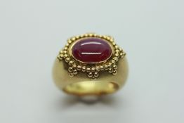 AN 18CT GOLD RING, SET WITH OVAL MAUVE STONE, SURROUNDED BY APPLIED BEADS.