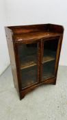 A SMALL OAK CUPBOARD, THE TWO GLAZED DOORS ENCLOSING A SHELVED INTERIOR W 60CM D 29CM H 89CM.