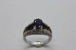 AN ELABORATE WHITE METAL DESIGNER DIAMOND SET DRESS RING SET WITH A CENTRAL BLUE STONE.