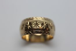 A 9CT GOLD PATTERNED WEDDING BAND.