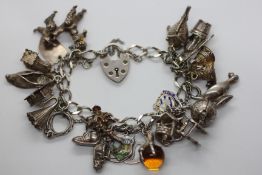 A SILVER CHARM BRACELET WITH APPROX 21 SILVER & WHITE METAL CHARMS.