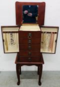 A MODERN MAHOGANY FINISH FLOOR STANDING JEWELLERY CHEST CONTAINING A QUANTITY OF COSTUME NECKLACES