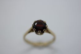 A 9CT GOLD DRESS RING SET WITH A GARNET.