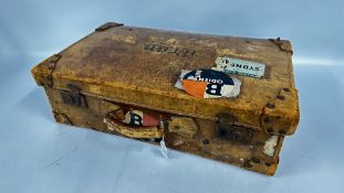 A VINTAGE LEATHER SUITCASE BEARING ORIGINAL LUGGAGE LABELS.