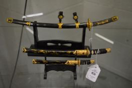 Miniature Japanese swords on stands.