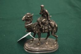 A small cast silvered metal model of a camel and rider.