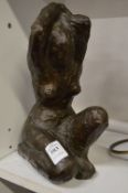 Crouching female nude with hands clasped above her head, cast bronze, appears unsigned.