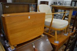 An Ercol light elm drop-flap occasional table and an Ercol armchair.