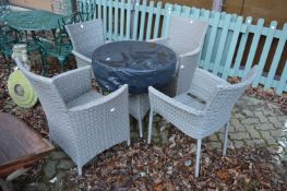 A small wicker style circular patio table and four armchairs.