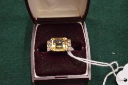 A stylish gold ring set with a emerald cut stone, possibly a citrine, flanked by three small
