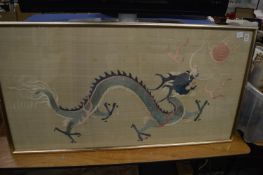 A Chinese embroidered picture of a dragon chasing the pearl of wisdom, framed and glazed.