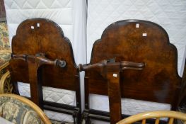 A pair of walnut single bed frames with bases and mattresses.