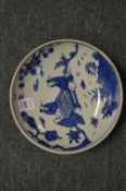 A Chinese circular blue and white dish painted with figures seated at a table.