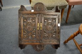 A carved oak two door hanging cupboard.